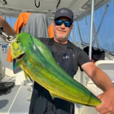 Person on a boat holding a large, colorful fish.